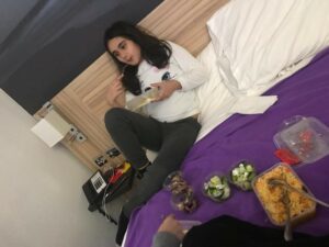 Zahra's daughter eating on the bed in their hotel room