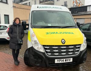 A woman standing next to an ambulance.